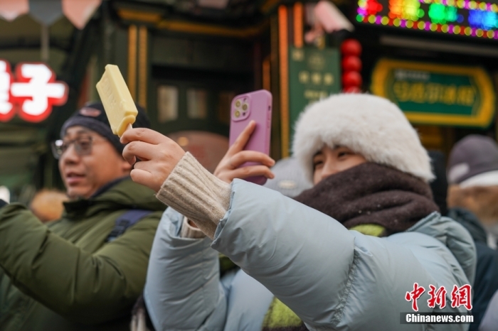 1月2日，在黑龙江哈尔滨中央大街，游客身着厚衣服在寒冷的天气中品尝雪糕，手拿雪糕拍照，成为哈尔滨冬日一景。图为游客拍摄雪糕。<a target='_blank' href='/'>中新社</a>发 赵宇航 摄